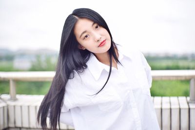 Portrait of beautiful woman with long black hair standing at building terrace