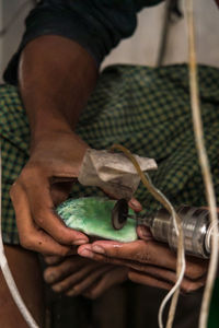 Midsection of craftsperson polishing gemstone