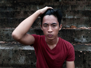 Portrait of young man with hand in hair sitting on steps