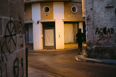 Rear view of man walking by building