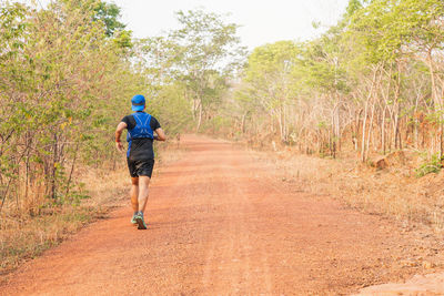 Full length rear view of man walking on road