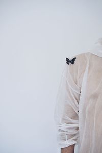 Midsection of man with artificial butterfly on shoulder against white background