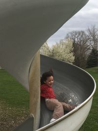 Low angle view of playful girl sliding in playground