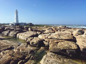 Lighthouse by sea against clear sky