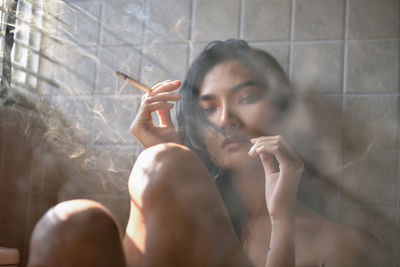 Portrait of young woman smoking in bathroom