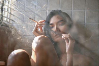 Seductive woman smoking cigarette at home