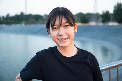 Portrait of smiling teenage girl standing by railing