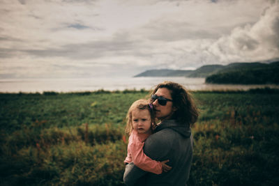 Portrait of mother and daughter on land against sky