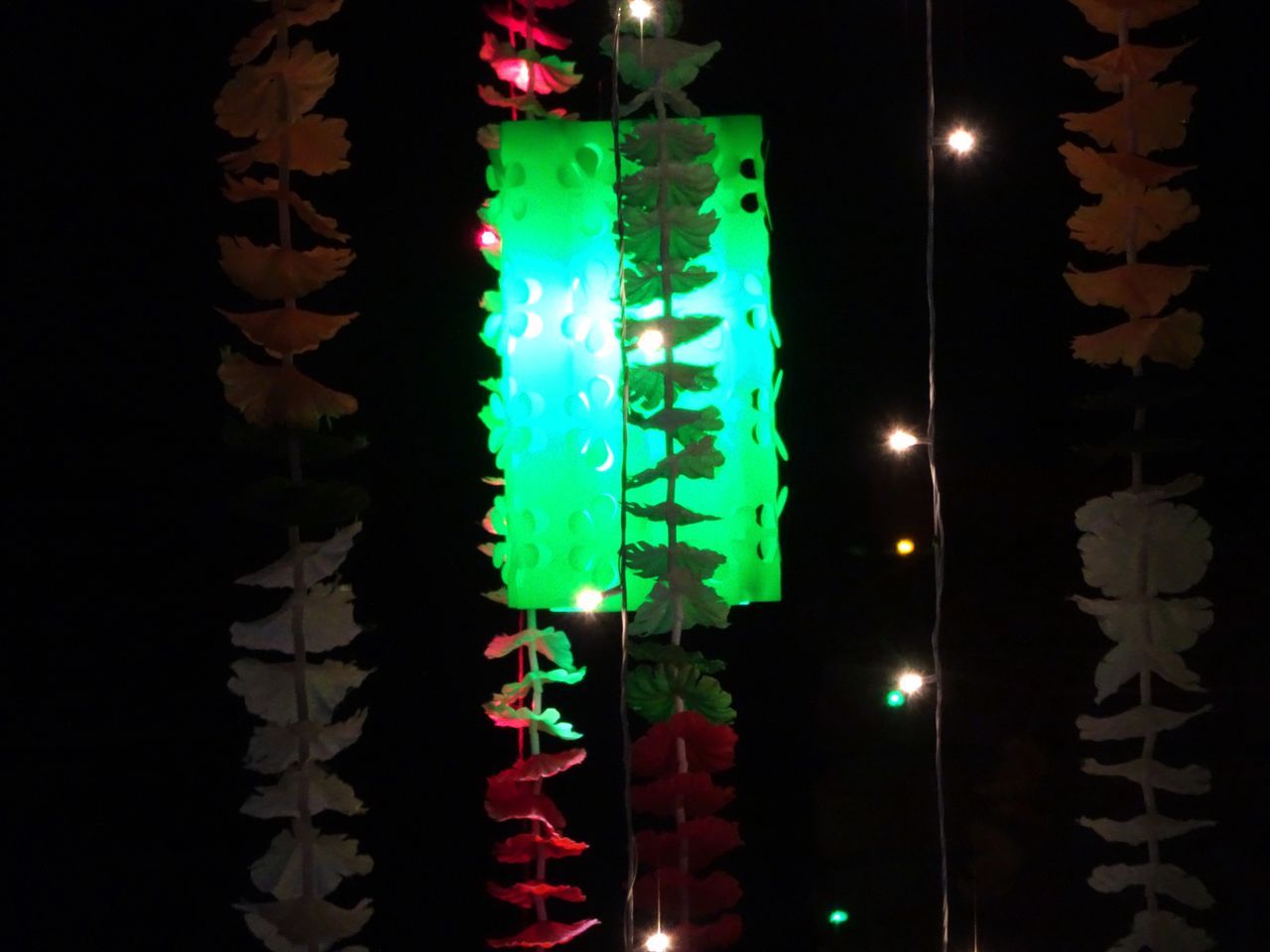 LOW ANGLE VIEW OF ILLUMINATED CHRISTMAS LIGHTS HANGING AT NIGHT