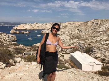 Woman in sunglasses standing on rock formation by bunker at sea