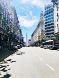 Road amidst buildings in city against sky