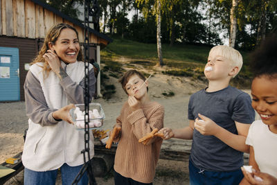 Children having snacks with counselor holding container at summer camp