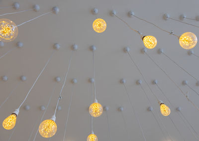 Low angle view of illuminated pendant light hanging on ceiling