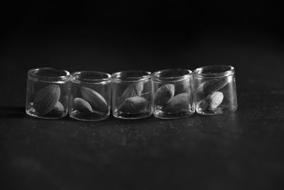 Almonds in glass containers on table against black background