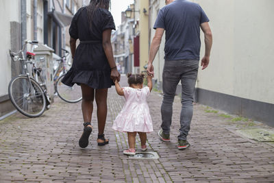 A young couple walking their daughter in european streets