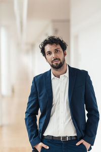 Male entrepreneur with hands in pockets standing in office