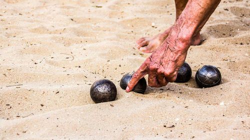 Low section of man playing with balls on sand at beach