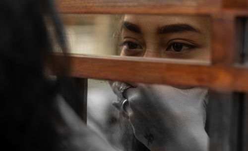 Close-up portrait of young woman looking through window