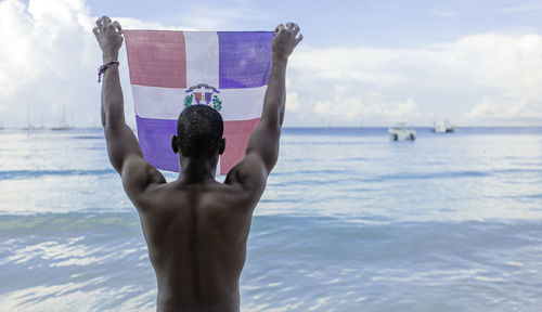 Low section of man with arms raised in sea