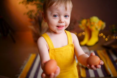Baby with easter eggs in yellow jumpsuit
