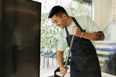 Smiling man with broom cleaning in coffee shop