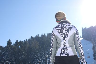 Rear view of woman standing on snow against clear sky