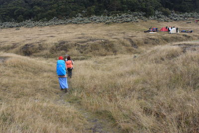 Rear view of women walking on field