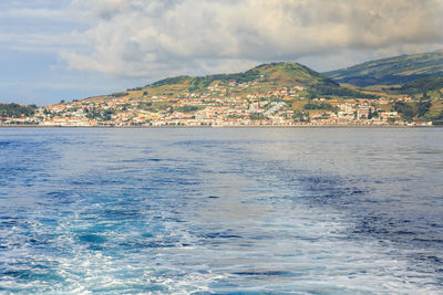 Scenic view of sea by buildings against sky