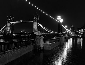 Rear view of people on suspension bridge at night