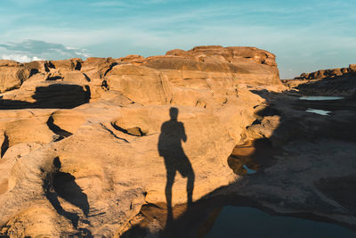 Rear view of man on rock formations against sky