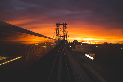 Railroad tracks against cloudy sky during sunset