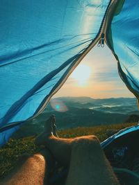Low section of man relaxing in tent at sunset