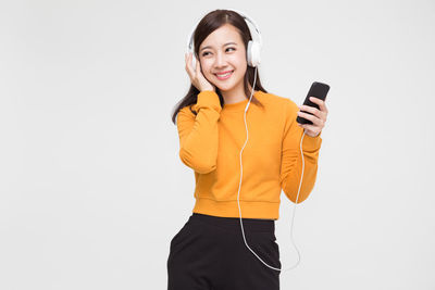 Portrait of smiling young woman using smart phone against white background