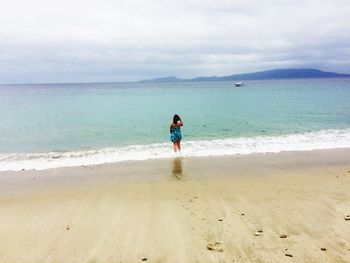 Rear view of man standing on beach against sky