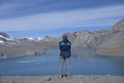 Rear view of man standing on mountain by lake