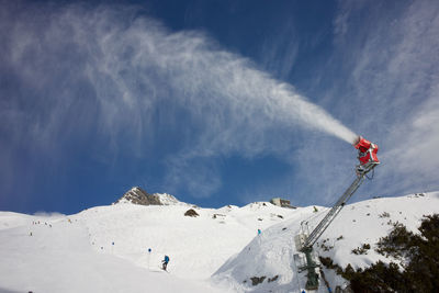 Artificial snow created by snow machine against sky