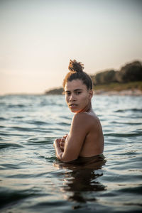 Portrait of woman in sea against sky during sunset