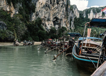 Row of old metal fishing boats with oars on shore of sea with beautiful mountains on background in vietnam