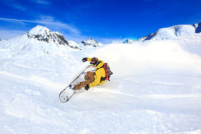 Man snowboarding on snowcapped mountain against sky