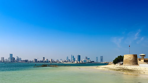 Sea and buildings against blue sky