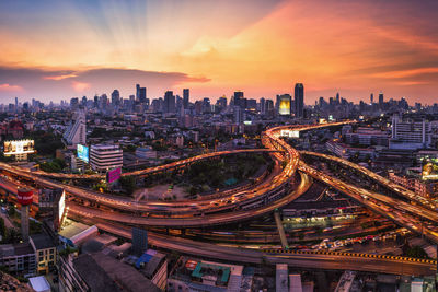 High angle view of illuminated multiple lane highway and buildings in city at dusk