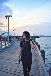 Full length of woman standing on pier over sea against sky