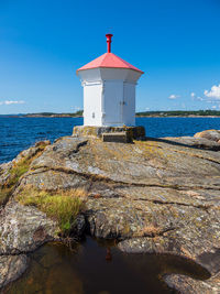 Lighthouse by sea against sky