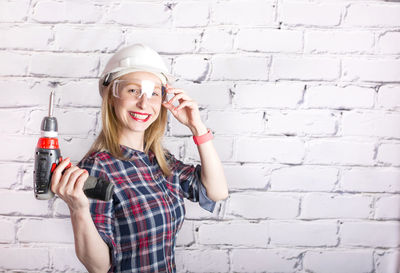 Young woman smiling while standing against wall