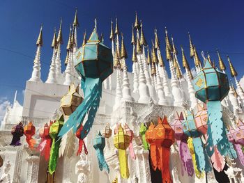 Low angle view of multi colored umbrellas hanging by building against sky