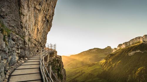 Scenic view of path in mountains against clear sky during sunrise 