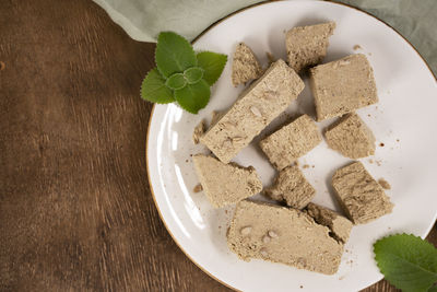 Traditional eastern sweets halva with sunflower seeds and mint leaves on a white plate. top view.