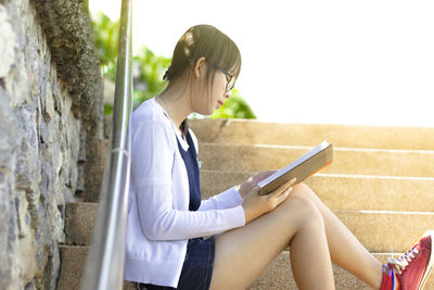 Side view of a young woman reading book