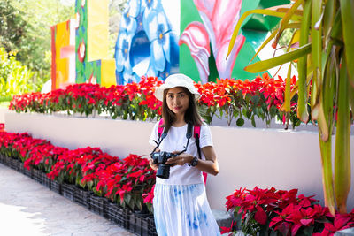 Portrait of woman standing by flowering plants