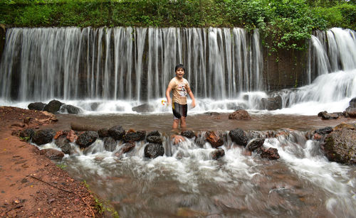 Rear view of woman standing against waterfall